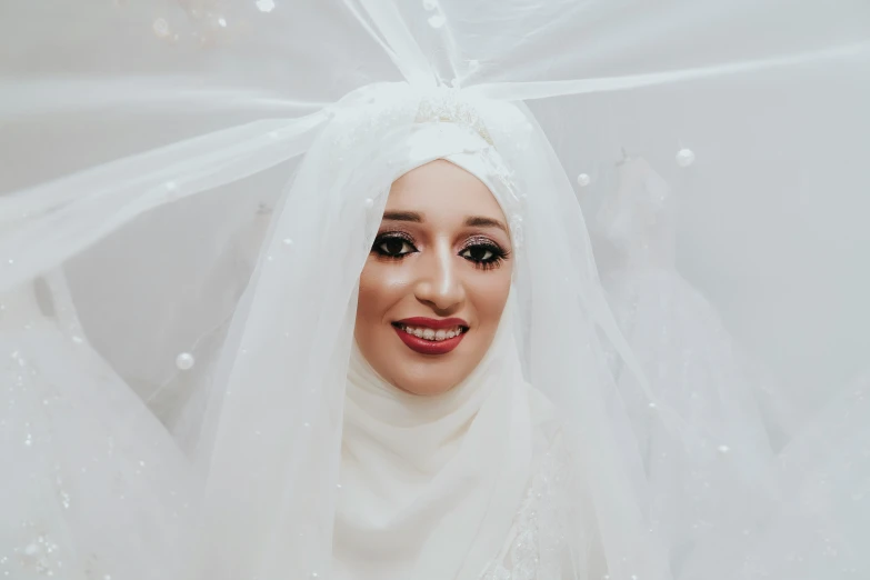 an attractive woman in white dressed in veils and headdress