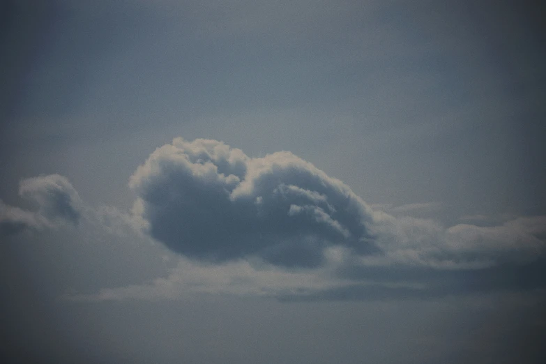 large fluffy clouds float above a jet in the sky