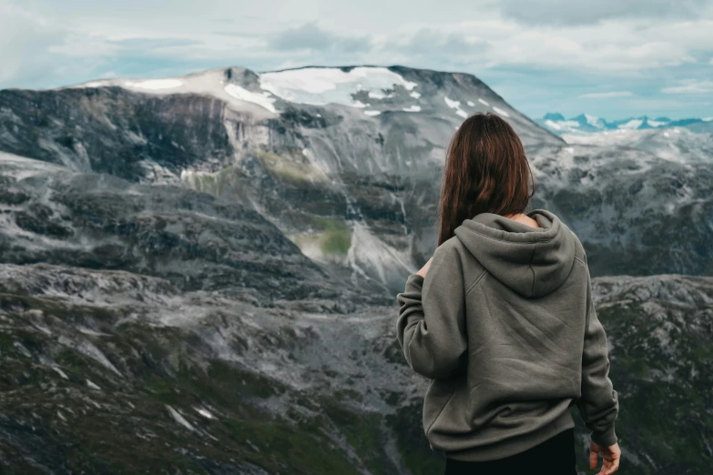 a woman in a hooded jacket looking at mountains and rocks