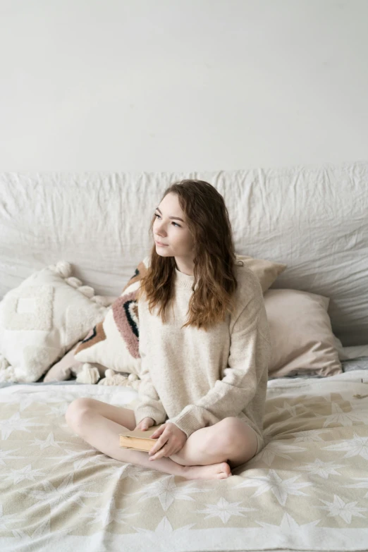 the woman is sitting on the bed using her cell phone