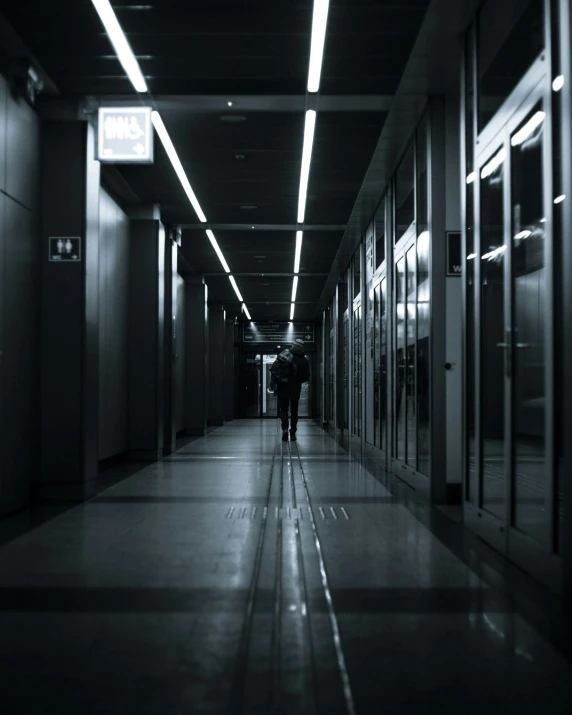 two people walk through a dimly lit hallway