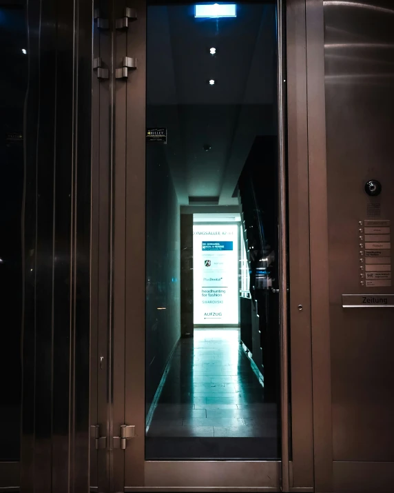 a metallic elevator with open doors at the end of it