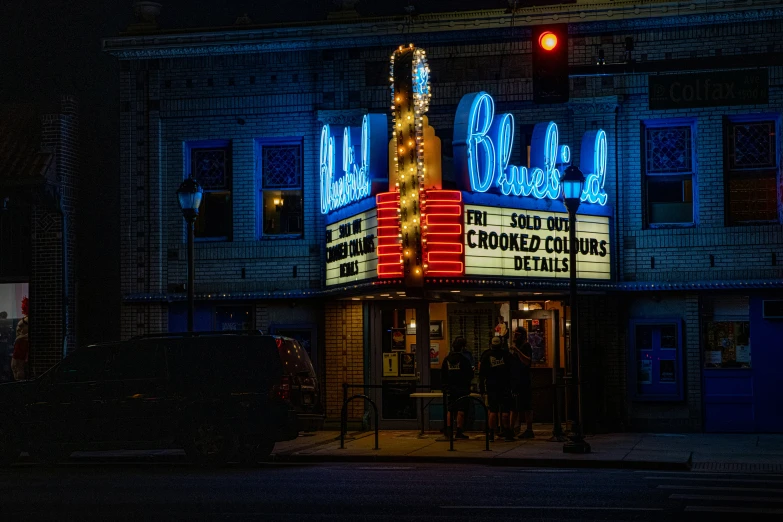 a theater in the night with its neon sign and a building behind it