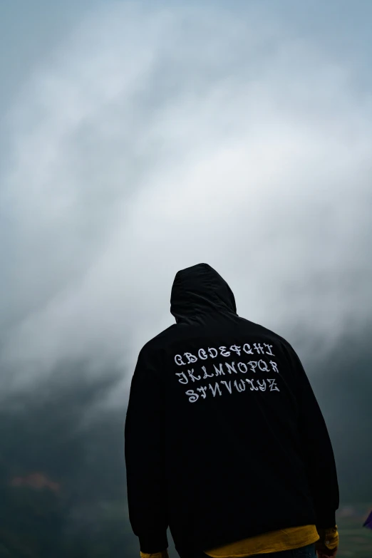 the person is standing under an umbrella and wearing a hoodie