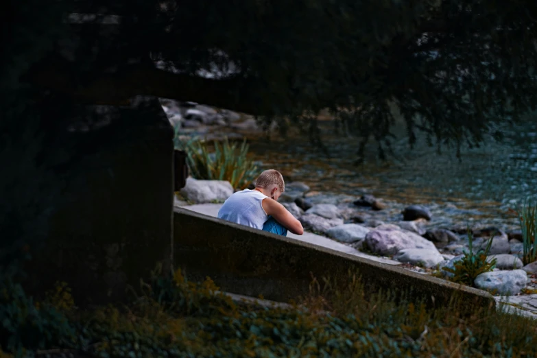 a child sitting on a stone wall by a pond