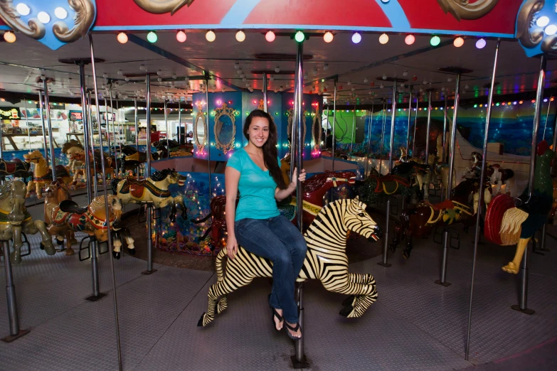 woman posing on an outdoor carousel in front of fake zes