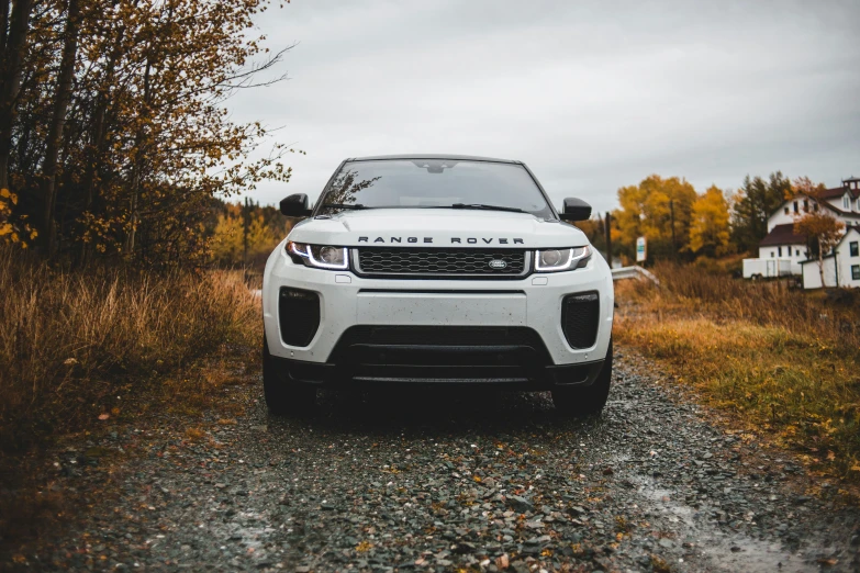 a white land rover parked in front of trees