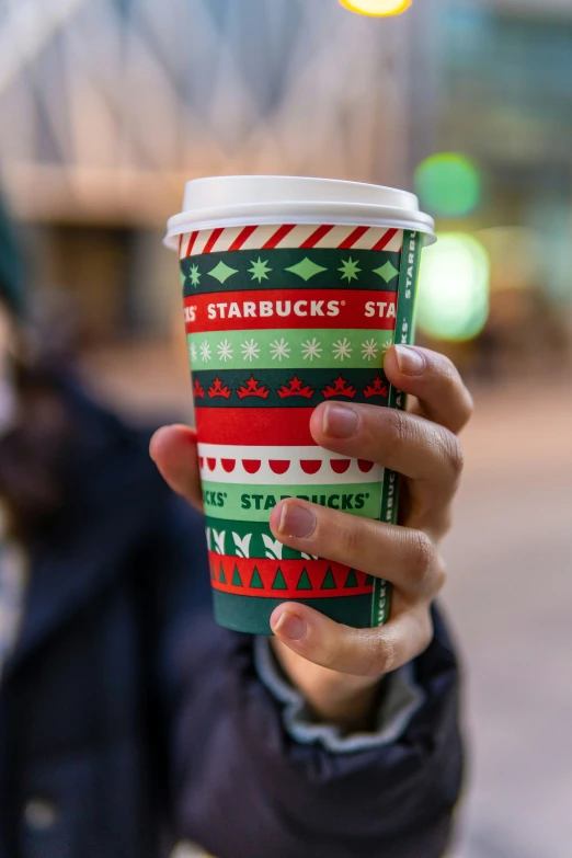 a person is holding a coffee cup with christmas print on it