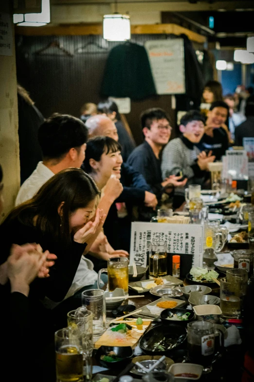 many people are gathered around a long table full of food