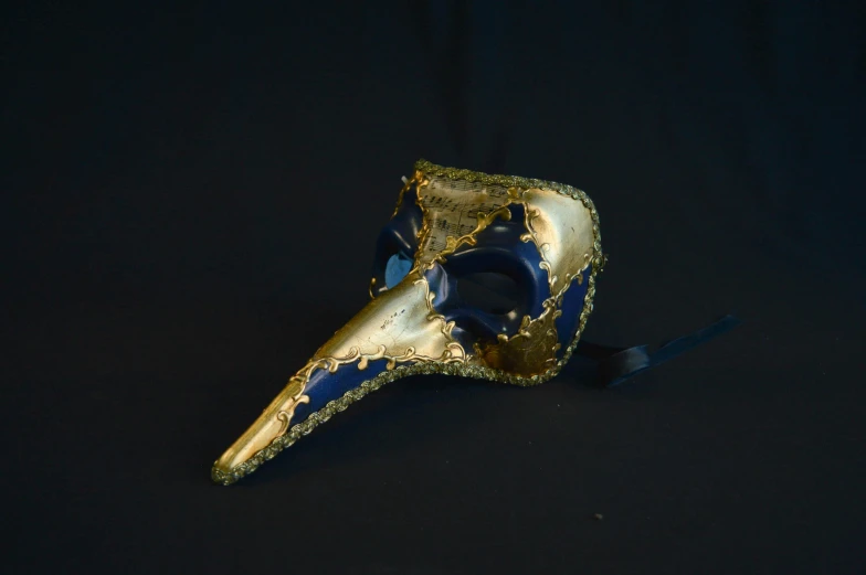 an artistically colored mask rests against a black backdrop