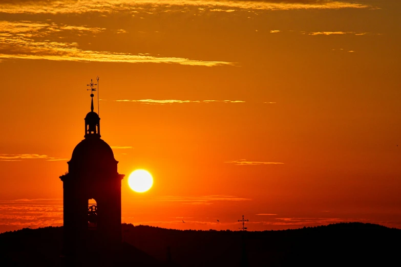 the sun is setting behind a clock tower