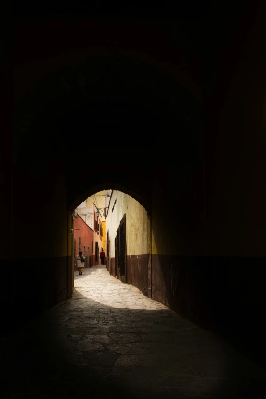 an alley way with a dark tunnel at the end