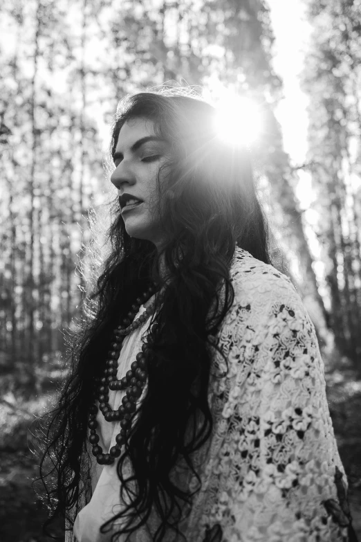 woman in the woods with sun shining through her eyes