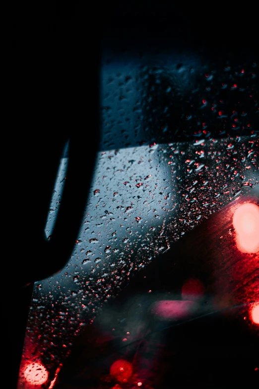 view of street lights in the rain through a windshield