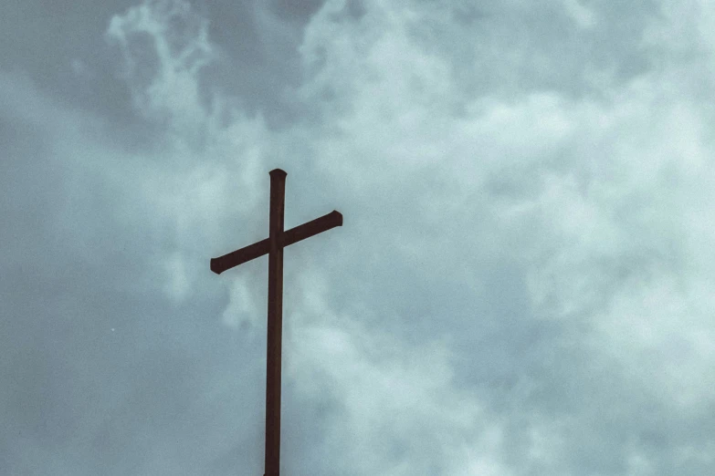 a cross on a cloudy day with the sky behind it