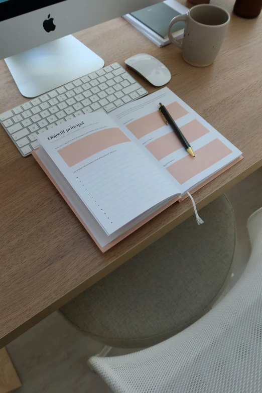 a computer monitor, keyboard, mouse and notebook with a cup of coffee