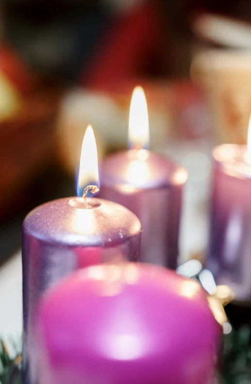 purple candles lit on a table with christmas decorations