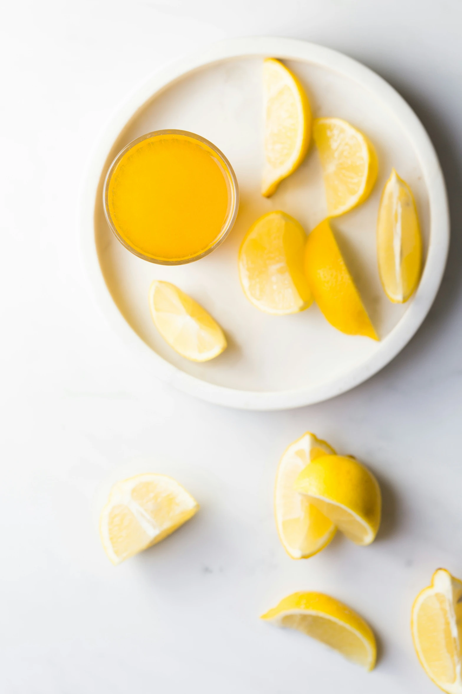 the sliced lemons and juice are on a white plate