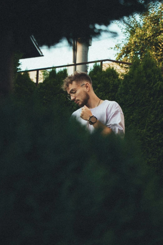 a man with glasses on is walking through some bushes