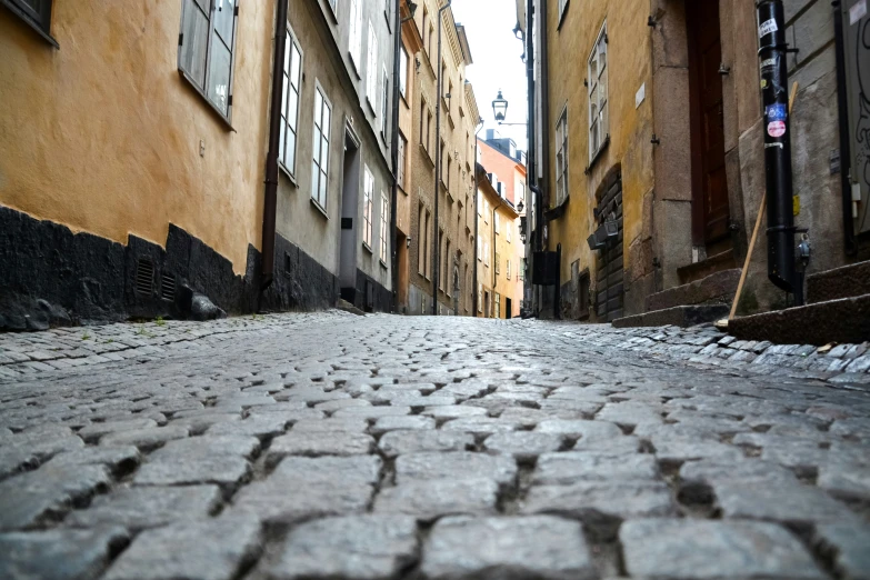 a cobblestone road surrounded by buildings in the distance