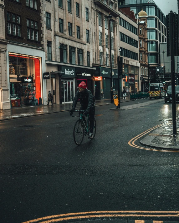 man riding his bike on a city street in the rain