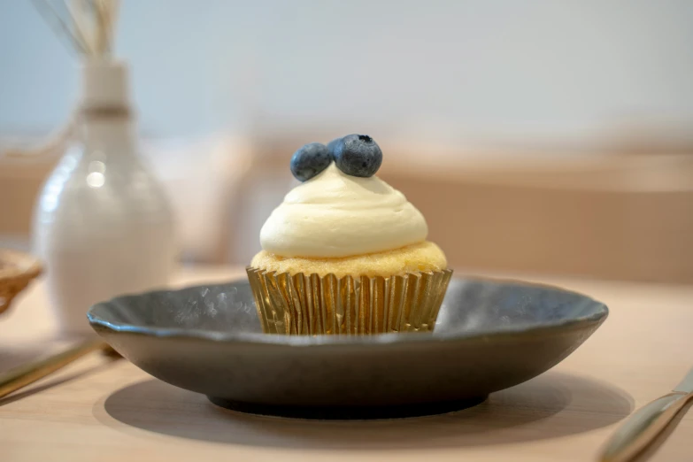 a cupcake with white frosting on a blue dish