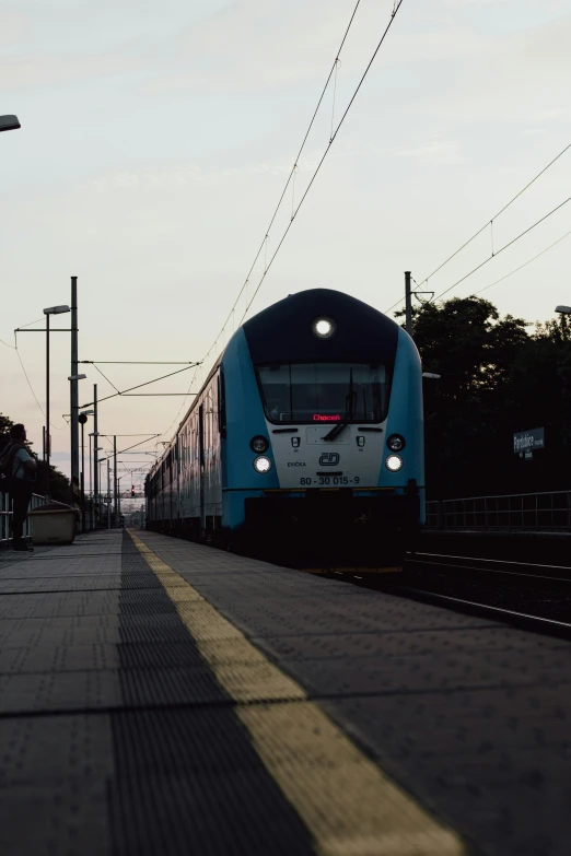 the blue and white passenger train is coming towards us