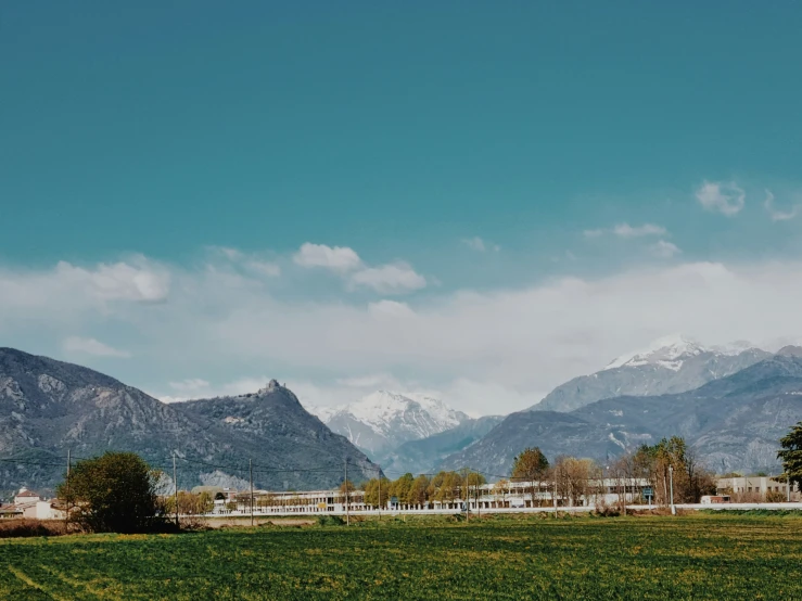 a lush green field surrounded by snow covered mountains