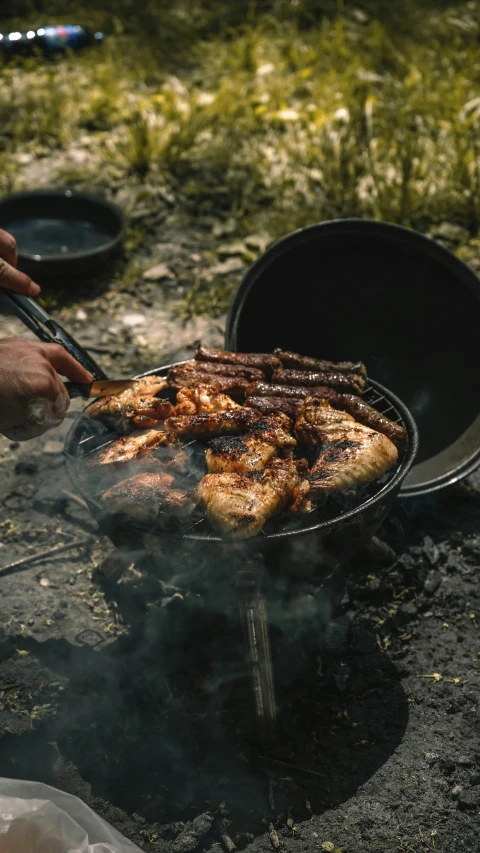 a man prepares food from a cooking grill outdoors