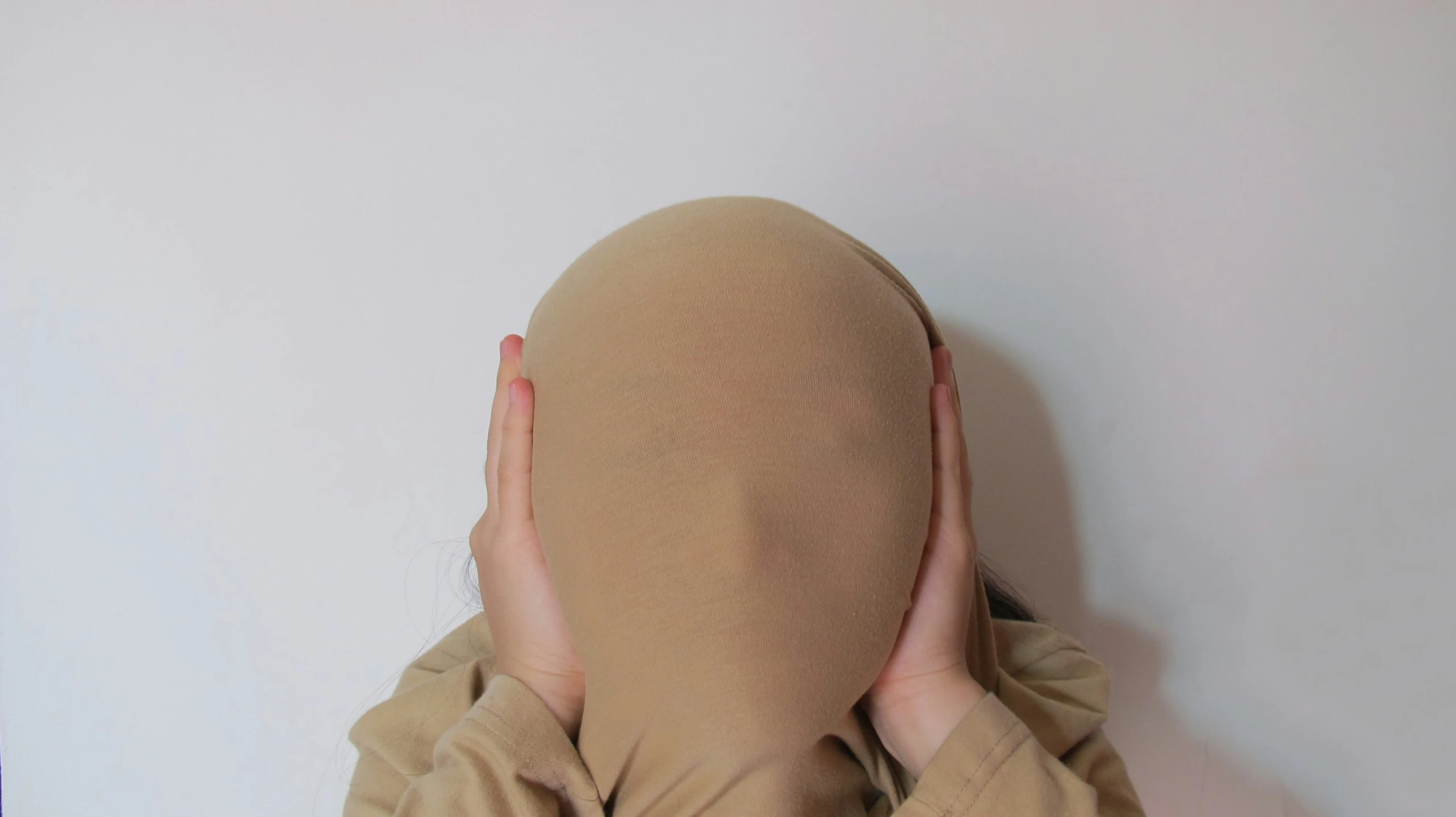 a person covers their face with a beige mask