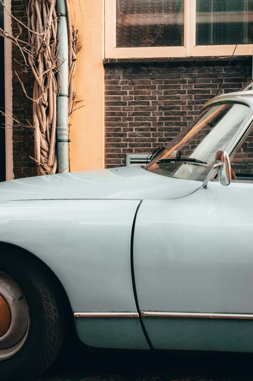 an old blue sports car parked in front of a building