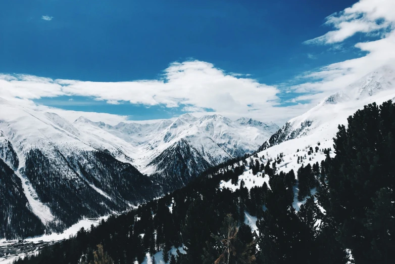 a scenic view of mountains, pine trees and a blue sky