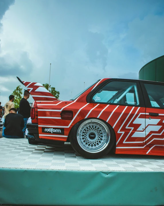 an orange and red car is parked at a show