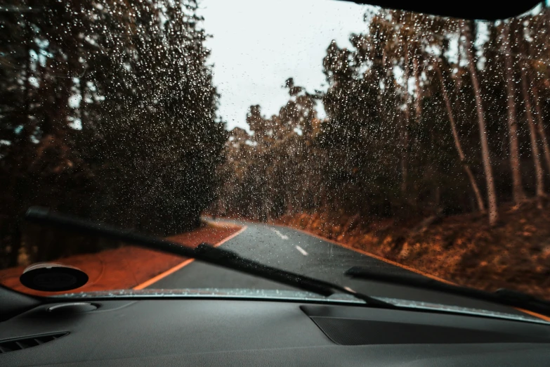 rain is falling on the windshield as seen from a vehicle