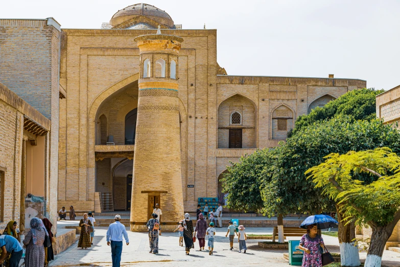 several people walk near the entrance of a building with arched archways