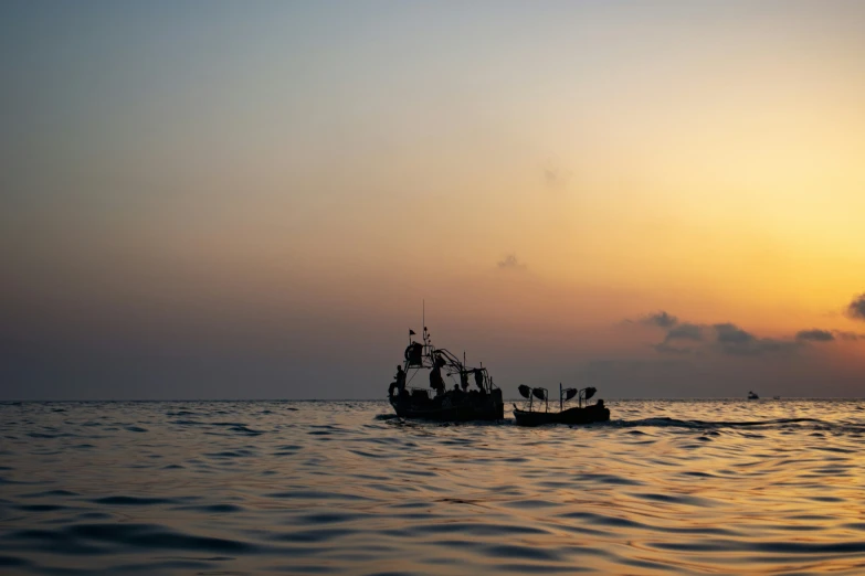 a boat sailing in the ocean during sunset