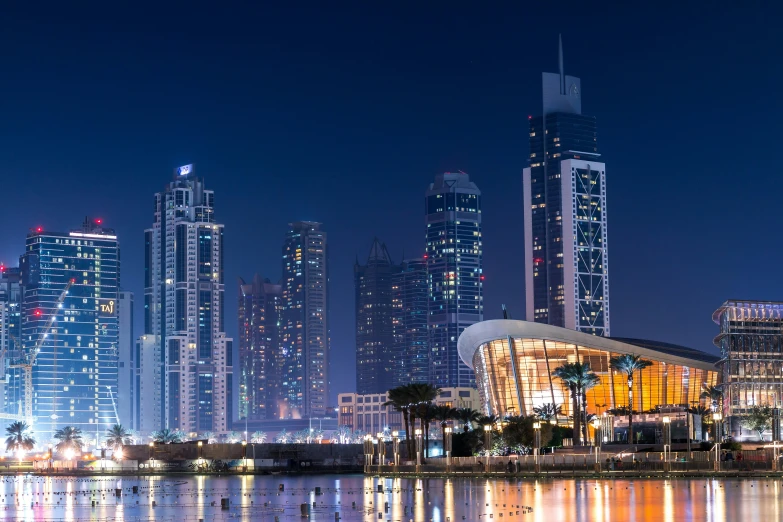 a nighttime skyline with many skyscrs and reflections in the water