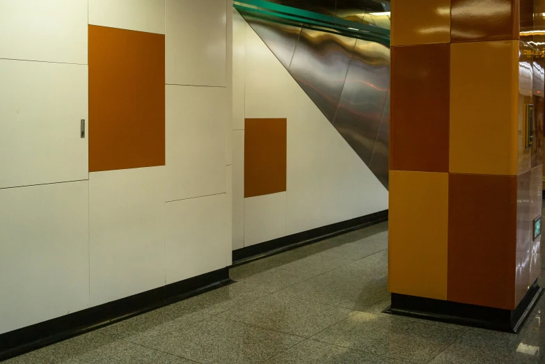 the hallway in a public building that is covered by an orange, yellow and grey colored wall