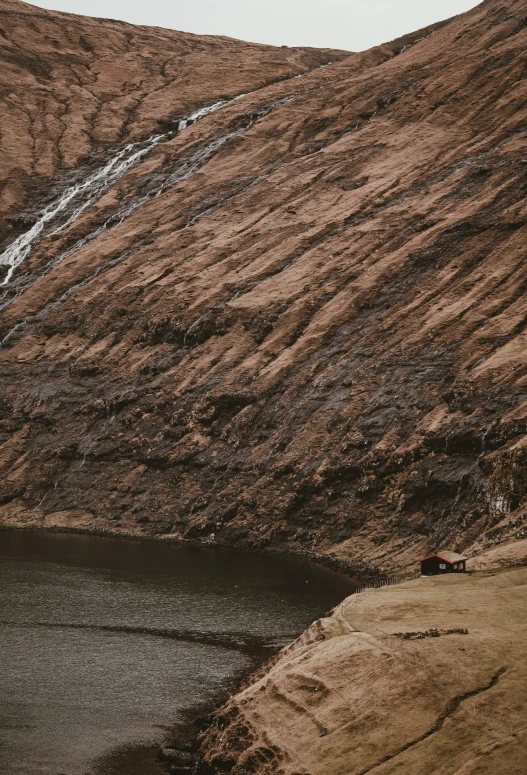 a lake sits at the base of an enormous cliff