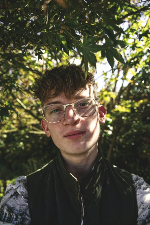 a young man wearing glasses sitting on the ground