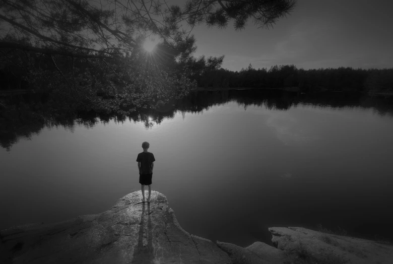 a boy looking out at a lake at night