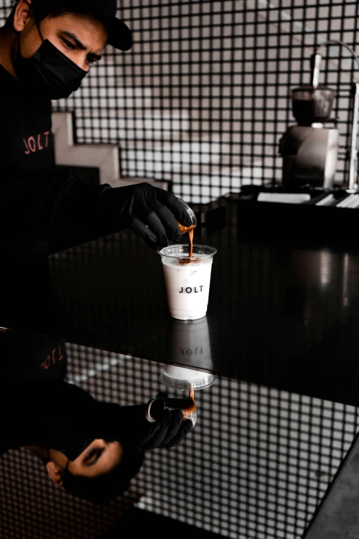 man putting ketchup on cup of drink sitting on table