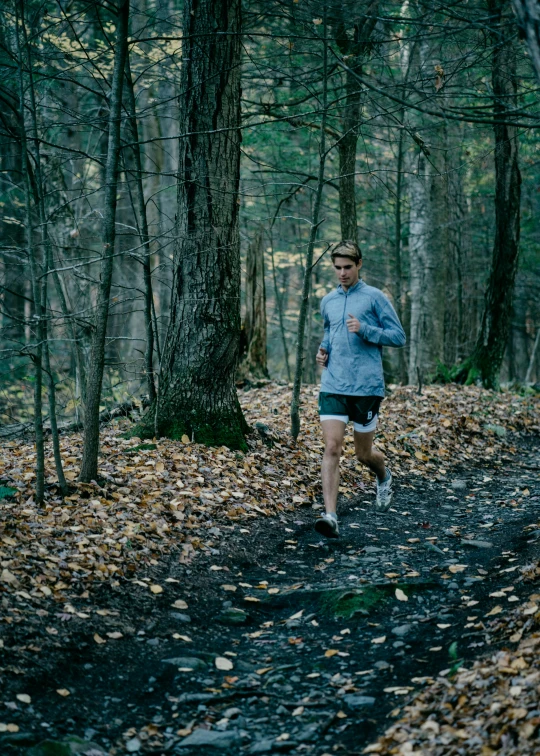 the man is jogging in the woods next to trees