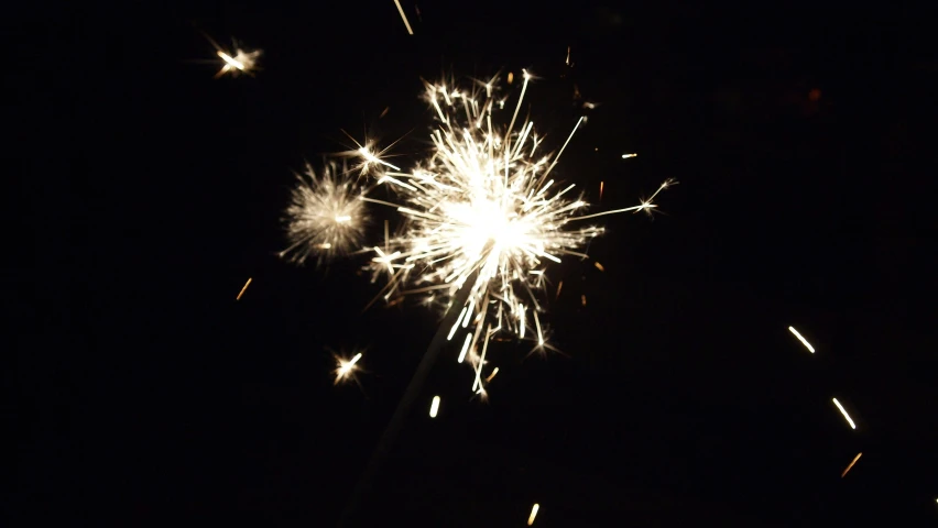 a white firework is seen in the dark sky