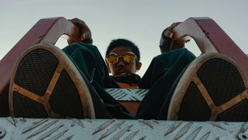 the feet of a person wearing sunglasses laying on top of a plane