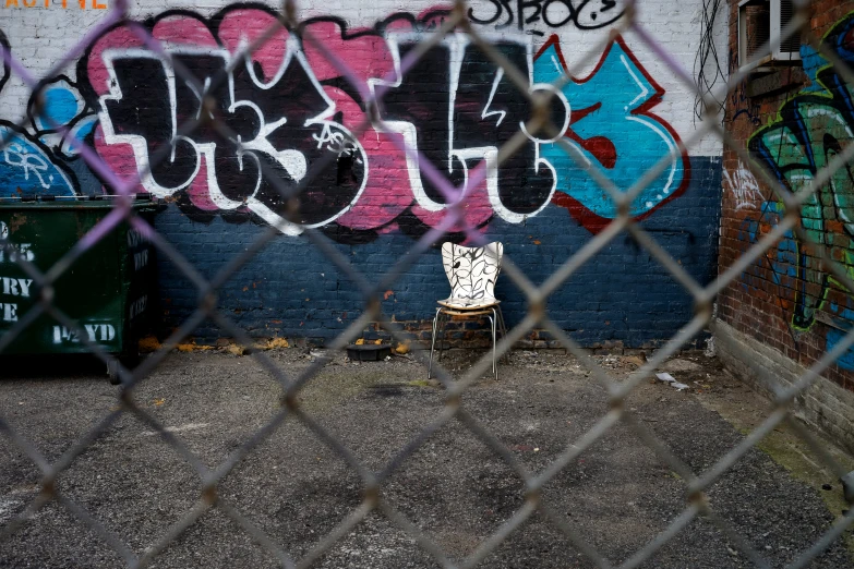 a chair with graffiti painted all over it behind a fence