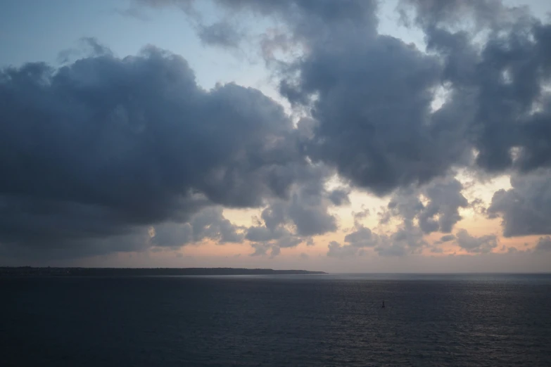 a beach with an island in the distance and some clouds in the sky