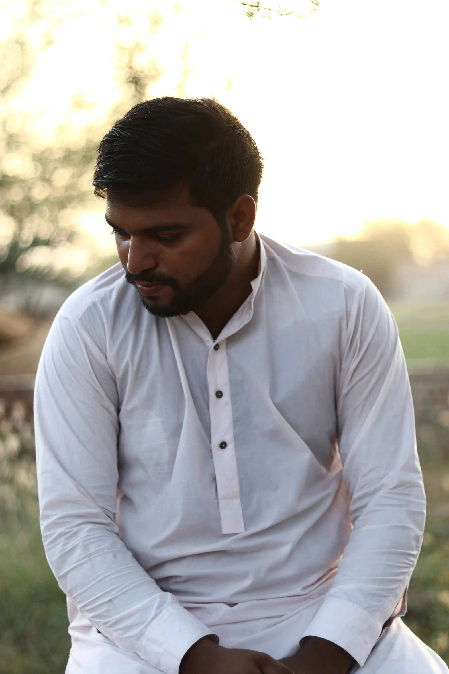 a man is sitting down in white clothes