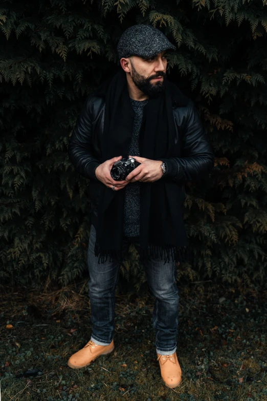 a man stands in the grass and holds a camera