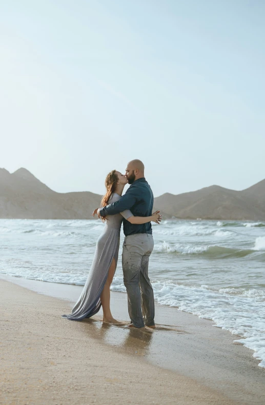 the man and woman are hugging each other on the beach